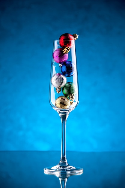 Free photo front view small xmas balls in wine glass on blue surface