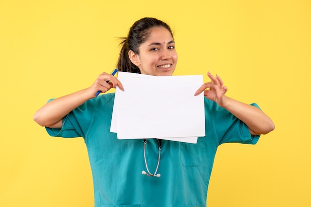 Front view smiled female doctor with documents on yellow background