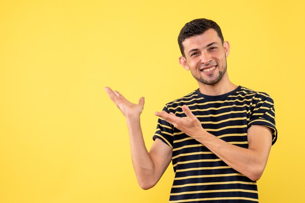 Front view smiled handsome male in black and white striped t-shirt yellow isolated background