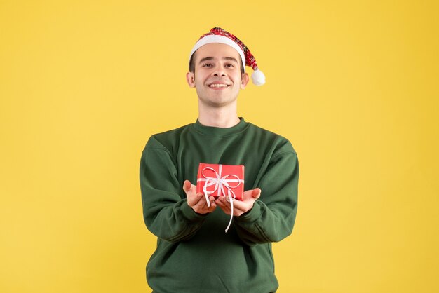 Front view smiled young man with xmas gift standing on yellow 