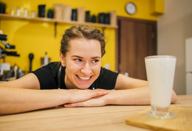 Free photo front view of smiley barista looking at glass of milk