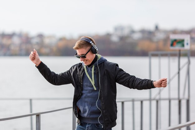 Front view smiley blonde man listening to music and dancing