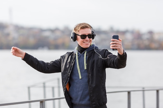 Foto gratuita uomo biondo di smiley di vista frontale che ascolta la musica all'aperto