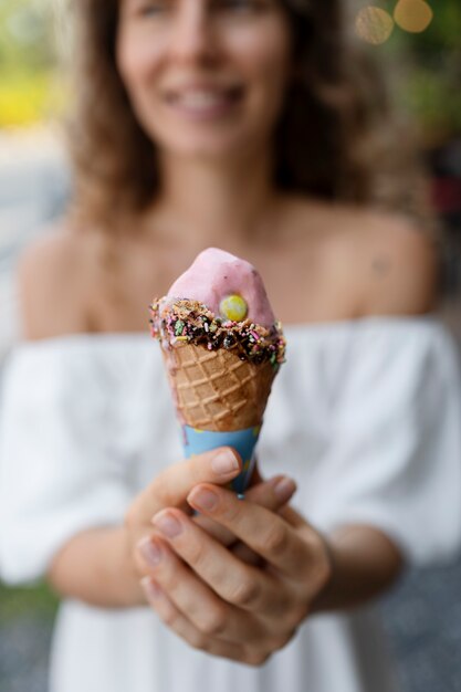 Front view smiley blurry woman holding ice cream