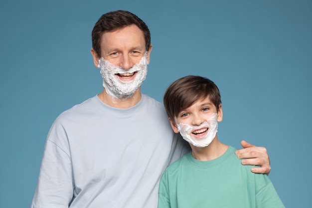 Free photo front view smiley boy and man with shaving cream