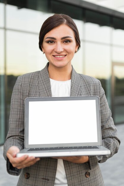 Front view of smiley businesswoman holding laptop