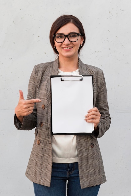 Free photo front view of smiley businesswoman pointing at notepad