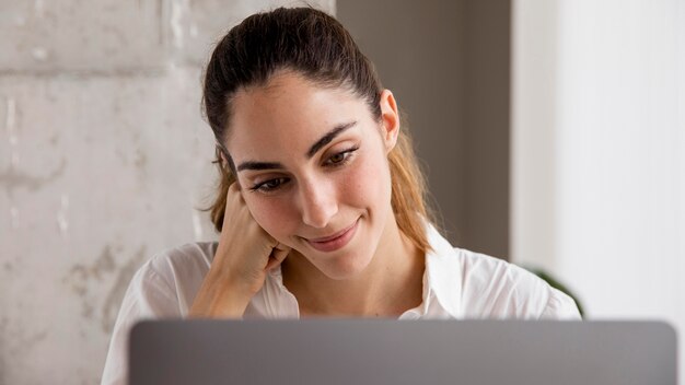 Front view of smiley businesswoman working on laptop