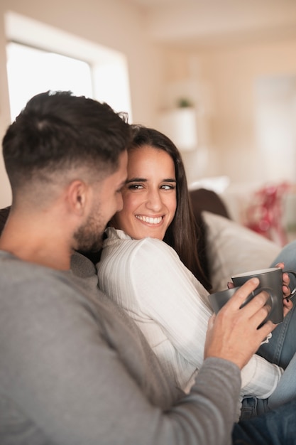 Front view smiley couple at home drinking coffee