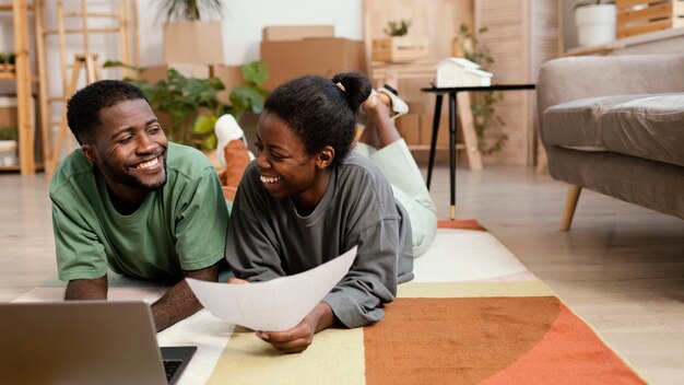 Front view of smiley couple making plans to redecorate house with laptop
