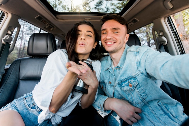 Coppia di smiley vista frontale prendendo selfie in auto