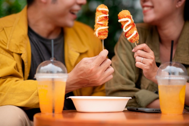 Free photo front view smiley couple with corn dogs