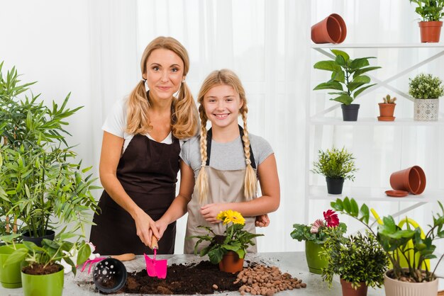 Front view smiley daughter and mom in greenhouse