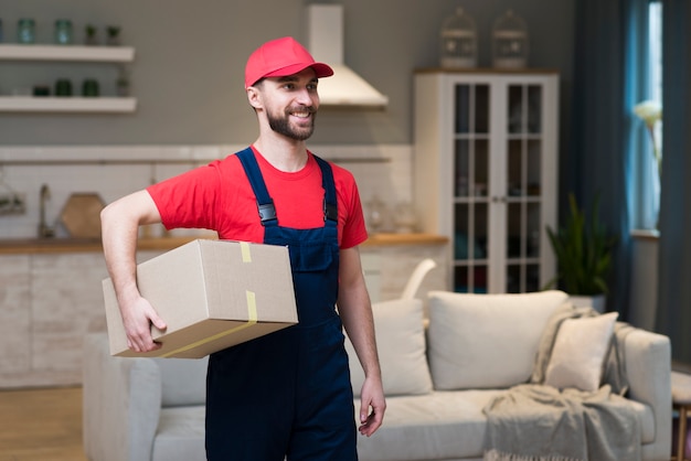 Front view of smiley delivery man holding boxes