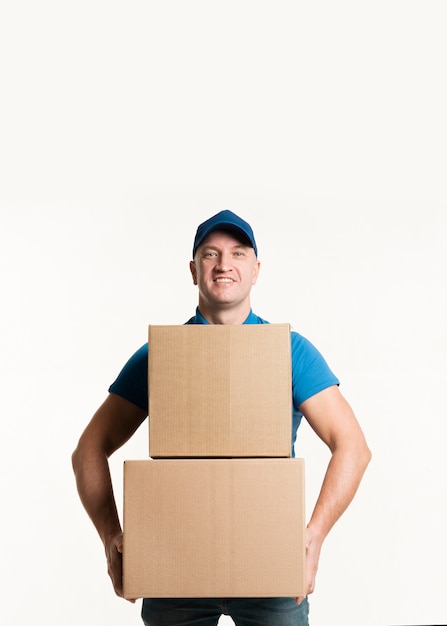 Front view of smiley delivery man holding cardboard boxes