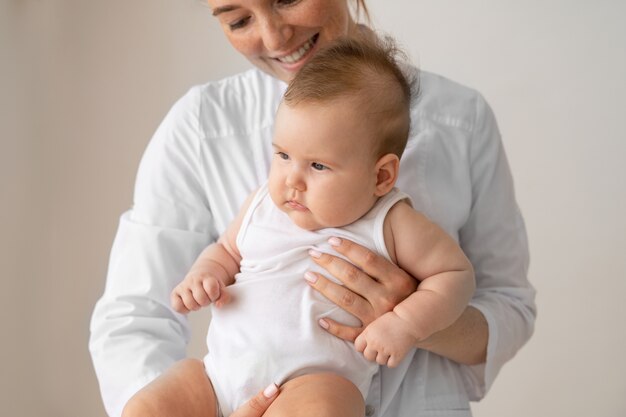 Front view smiley doctor holding baby