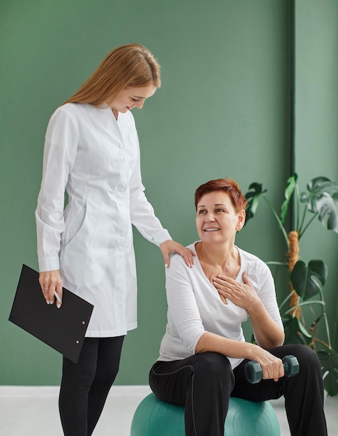 Front view of smiley elder woman in covid recovery with nurse