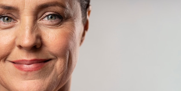 Free photo front view of smiley elder woman posing with make-up on and copy space