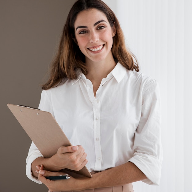 Front view of smiley elegant businesswoman holding clipboard