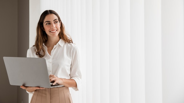 Front view of smiley elegant businesswoman using laptop with copy space