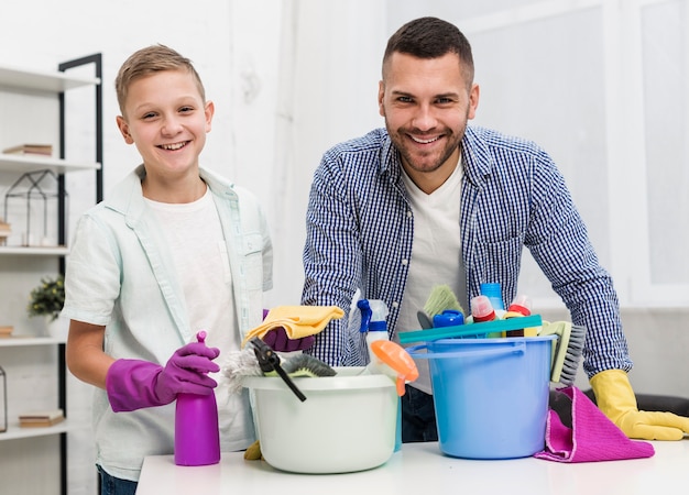 Foto gratuita vista frontale del padre e del figlio di smiley che propongono con i prodotti per la pulizia