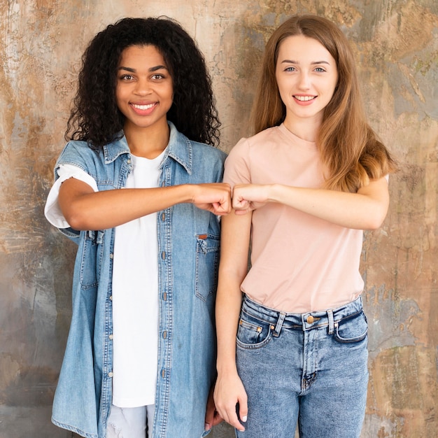 Free photo front view of smiley female friends fist bumping