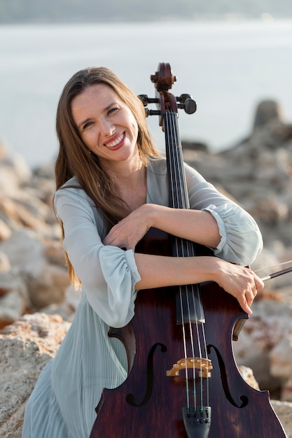 Front view of smiley female musician with cello