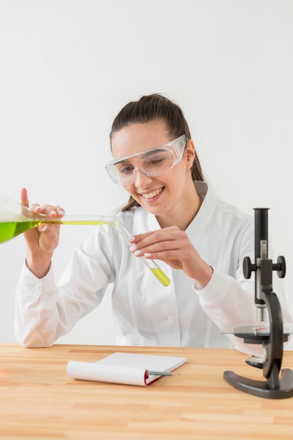 Front view of smiley female scientist analyzing potions in tubes