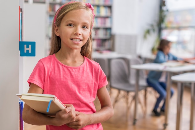 Free photo front view smiley girl holding a book and a notebook