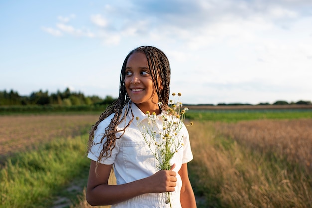 Foto gratuita fiori della holding della ragazza di smiley di vista frontale