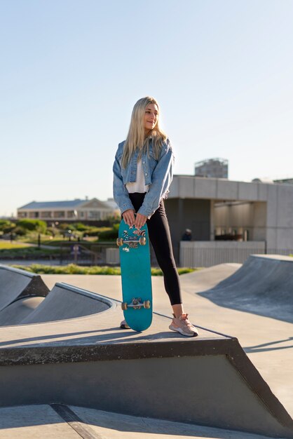 Front view smiley girl holding skateboard