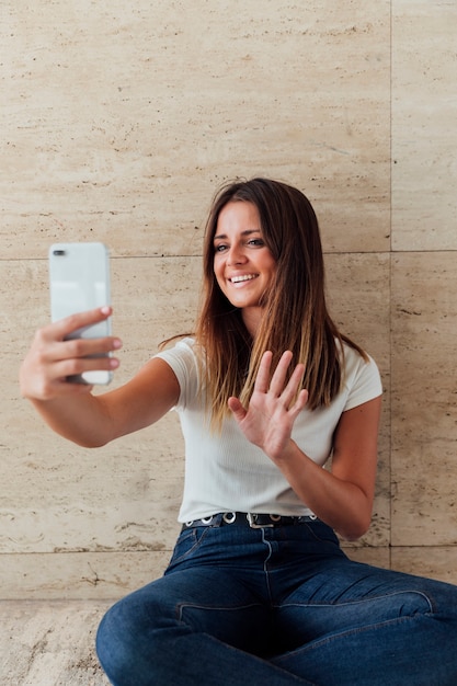 Free photo front view smiley girl waving at phone