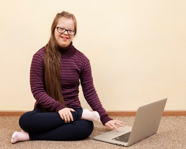 Vista frontale della ragazza di smiley con sindrome di down e laptop