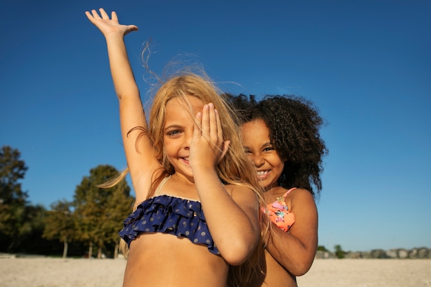 Free photo front view smiley girls on beach