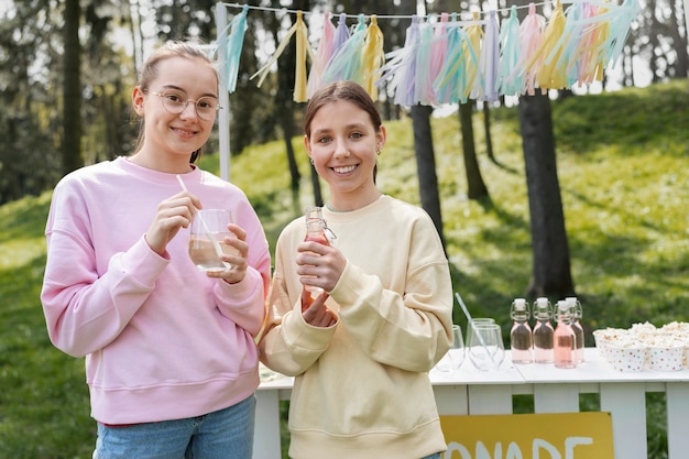 Front view smiley girls drinking lemonade