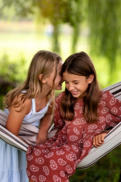 Free photo front view smiley girls sitting in hammock