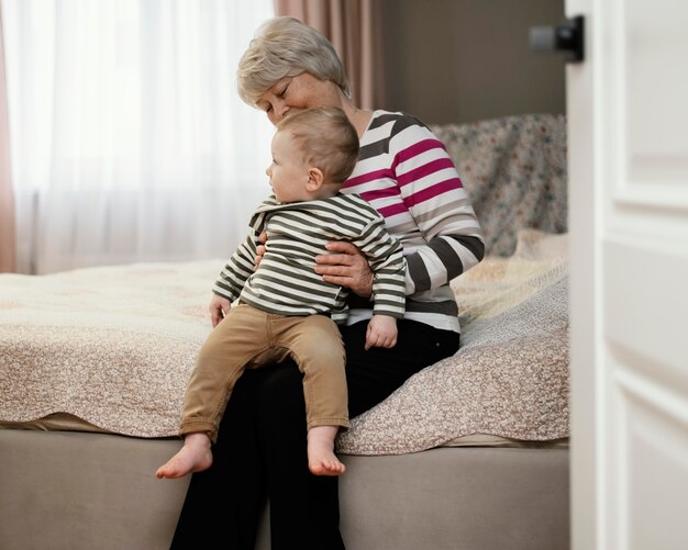 Front view of smiley grandmother holding her grandson