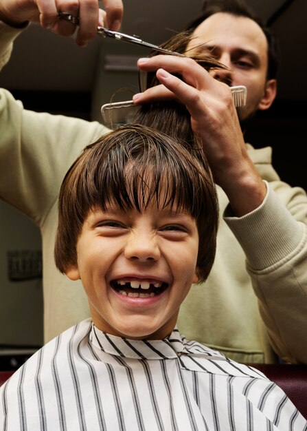 Ragazzo sorridente di vista frontale che ottiene taglio di capelli