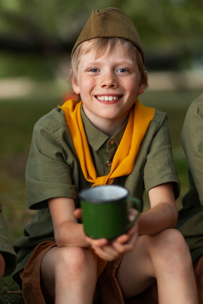 Foto gratuita tazza della holding del bambino di smiley di vista frontale