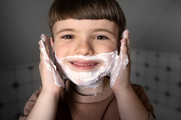 Front view smiley kid using shaving cream