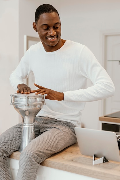 Free photo front view of smiley male musician at home playing drums