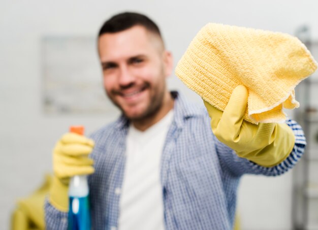 Front view of smiley man cleaning with rag