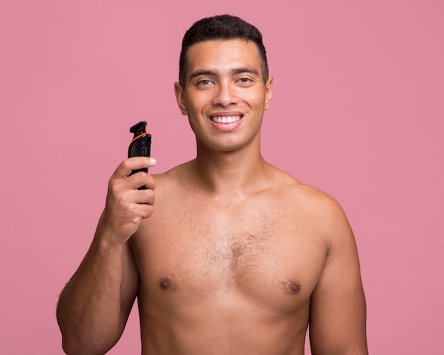 Front view of smiley man holding an electric shaver