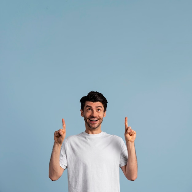 Free photo front view of smiley man looking and pointing up