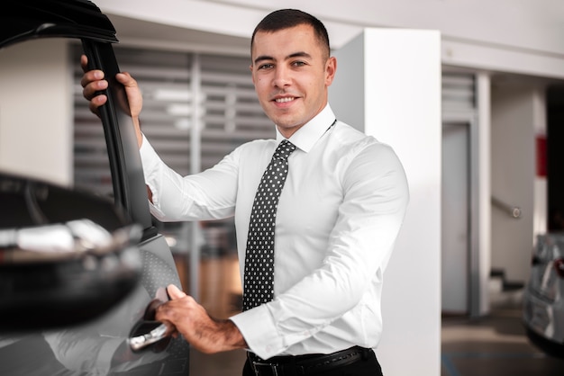 Free photo front view smiley man opening car door