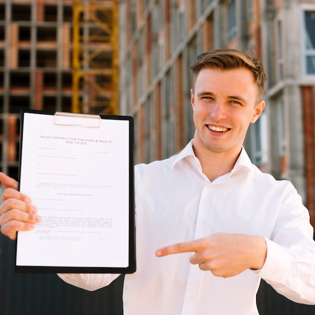 Free photo front view smiley man pointing at contract