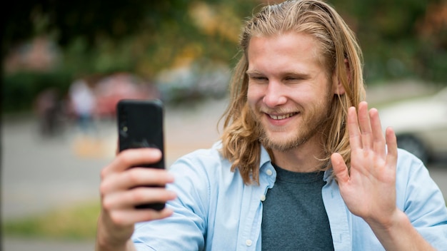 Vista frontale dell'uomo di smiley che prende selfie all'aperto