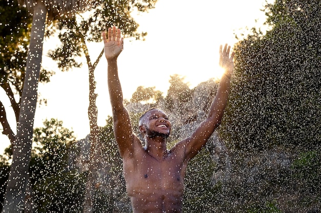 Foto gratuita uomo sorridente di vista frontale che fa la doccia all'aperto