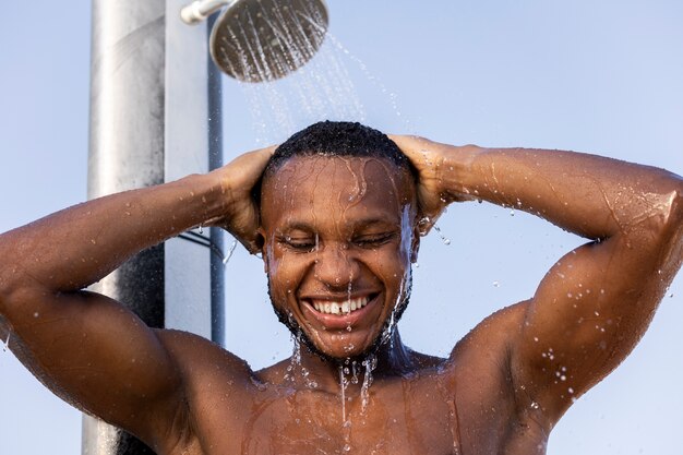 Free photo front view smiley man taking shower outside