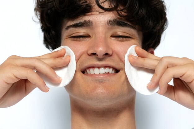 front view smiley man using cotton pads